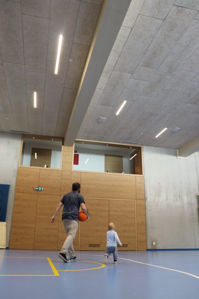 Erwachsener und Kind spielen Ball in der Sporthalle