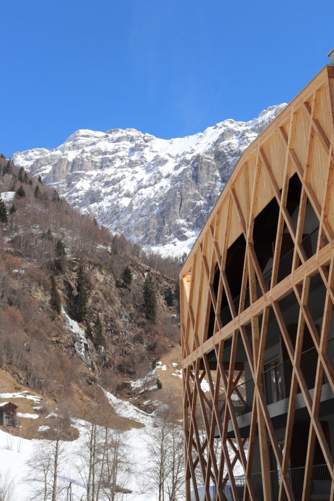 Holzfassade des Resorts vor verschneiten Berggipfeln