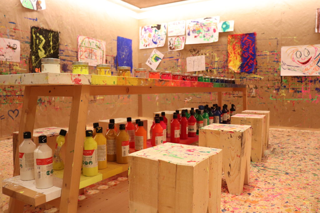 Kreativraum mit Kinderbildern an der Wand und Farbflaschen
