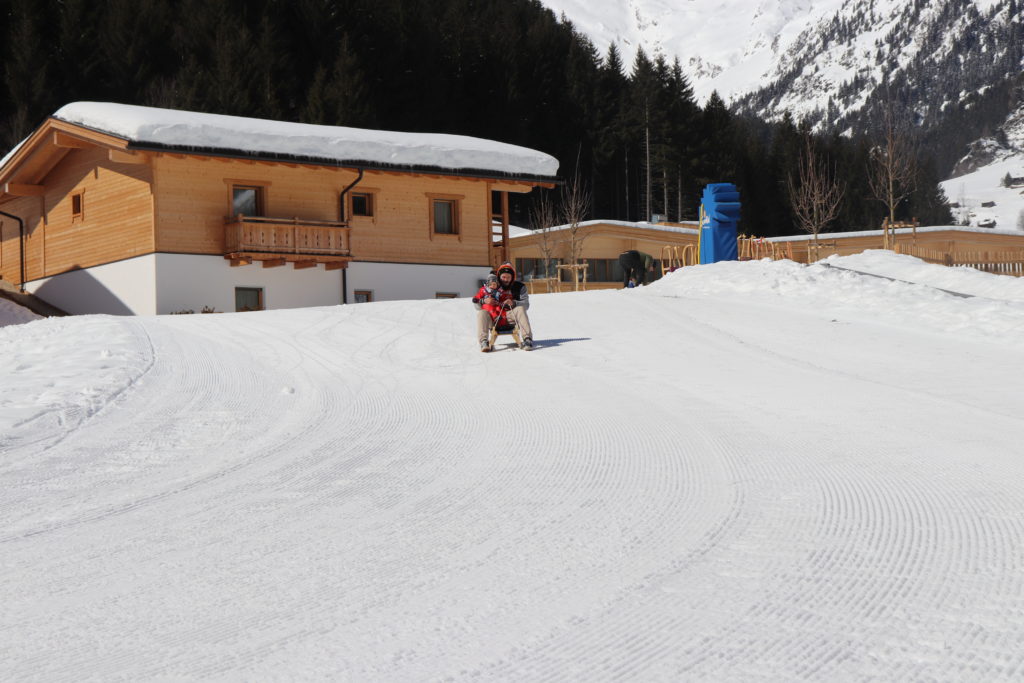 Verschneite Piste vor den Chalets des Resorts