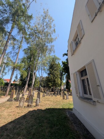 Seitlicher Blick über die Gräber zum Gebäude am jüdischen Friedhof Laupheim