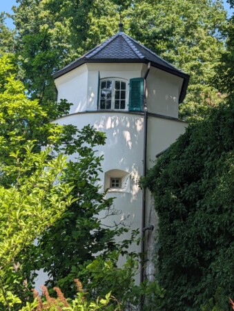 Weißer Turm mit grünen Fensterläden im Schlosspark Laupheim