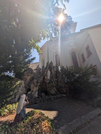 Lourdesgrotte mit Marienfigur neben einer Kirche in Laupheim