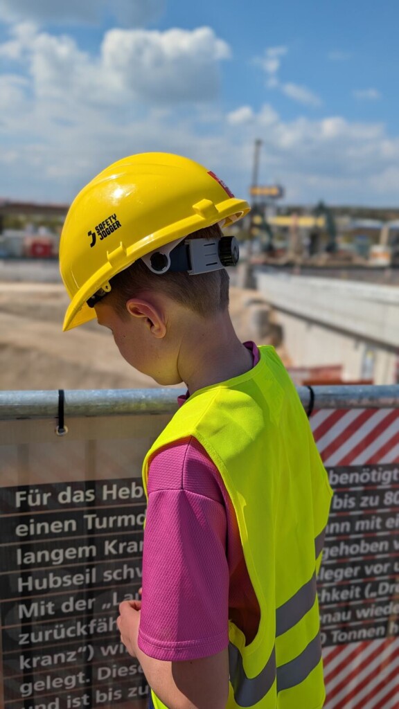 Kind mit gelbem Bauhelm auf der B10-Baustelle