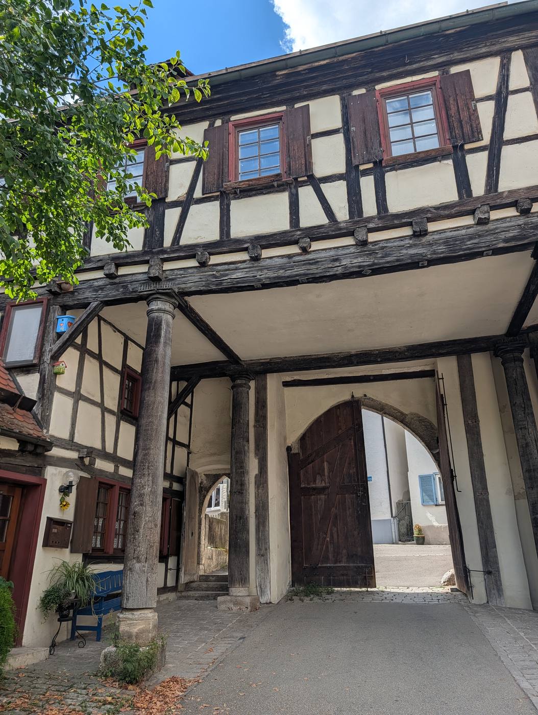 Fachwerk-Torhaus mit Holzs&auml;ulen und ge&ouml;ffnetem Tor in der Altstadt von Blaubeuren
