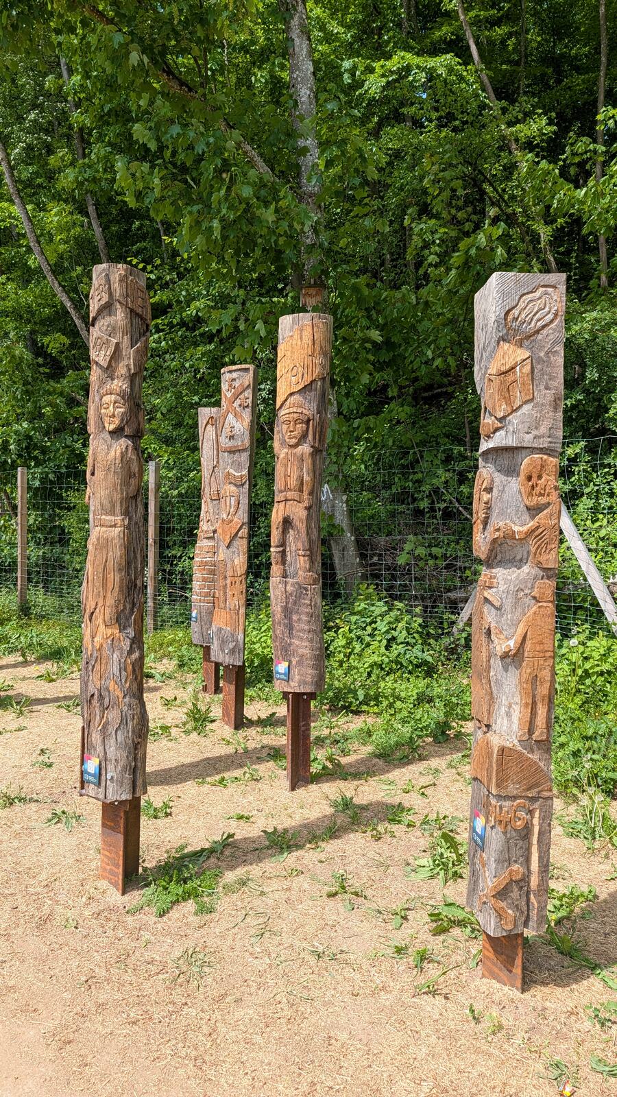 Geschnitzte Holzpfaehle auf der Wiese
