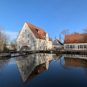 Historisches Gebaeude spiegelt sich im Wasser in Krumbach