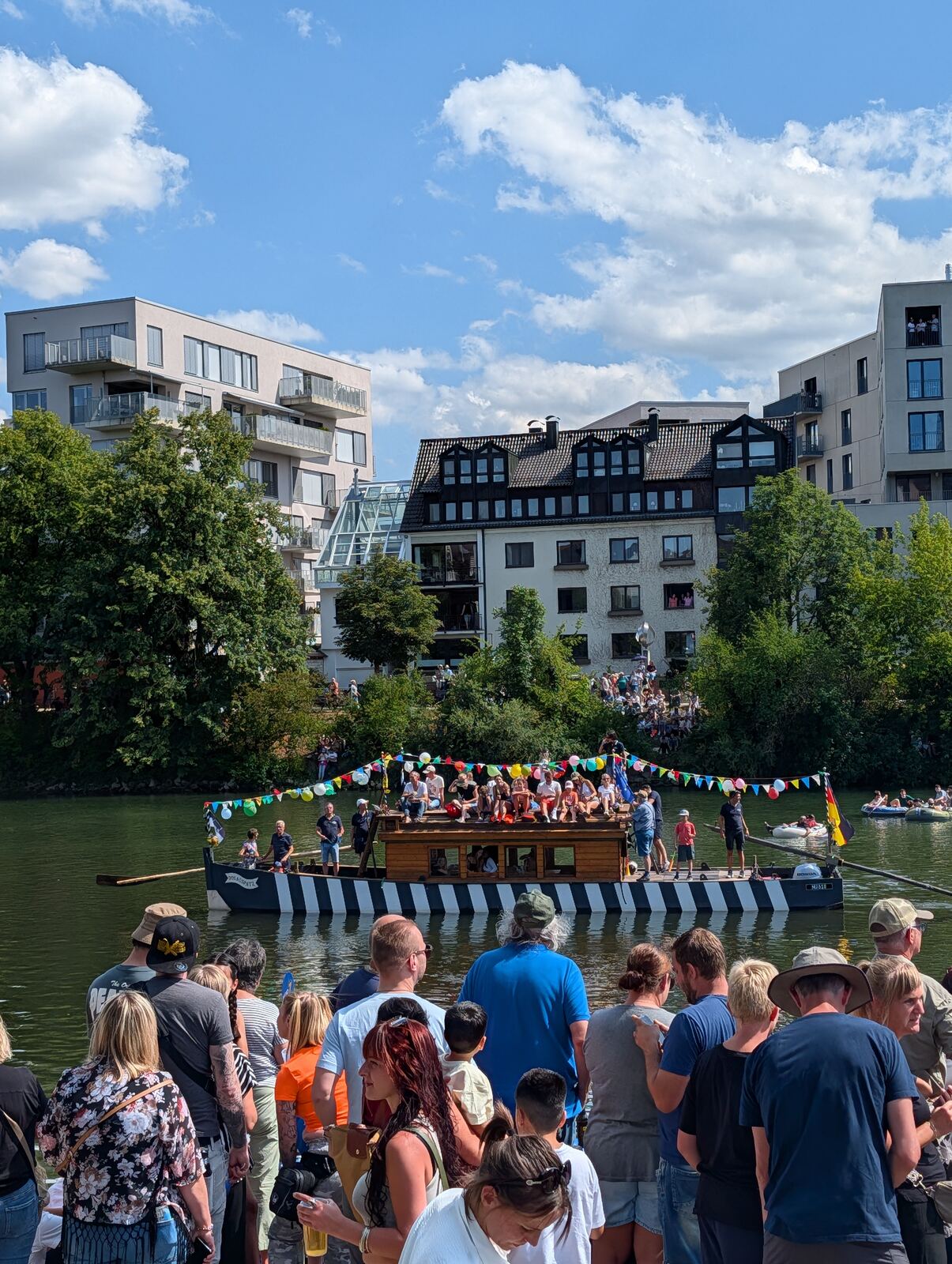 Geschmuecktes Nabada-Boot mit Wimpelkette auf der Donau, Zuschauer am Ufer