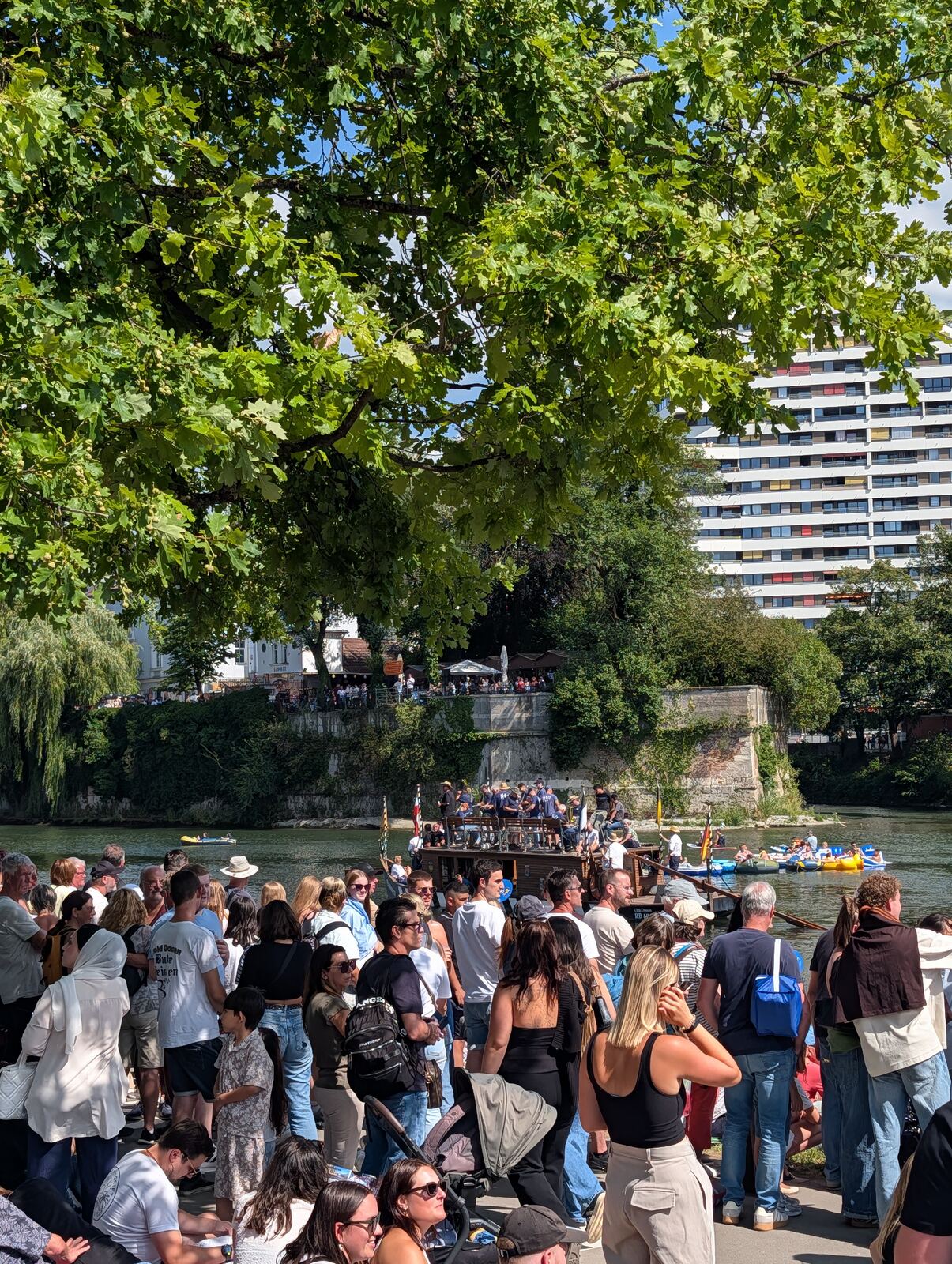 Zuschauer unter Baeumen am Donauufer beim Nabada in Ulm