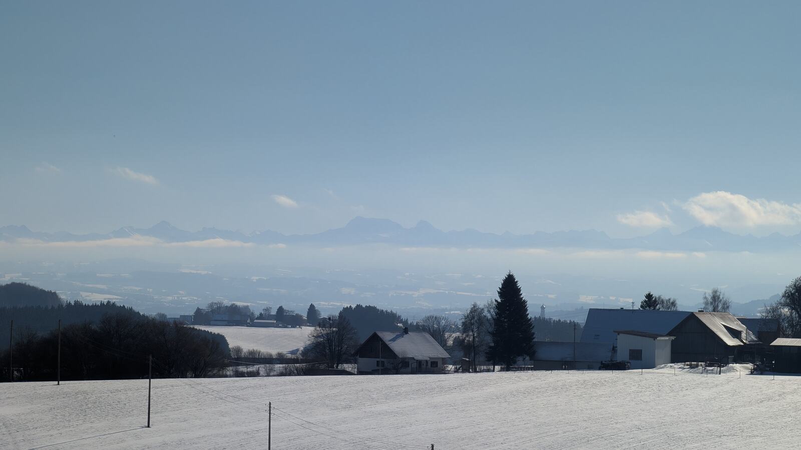 Blick ueber die verschneite Landschaft bis zu den Alpen