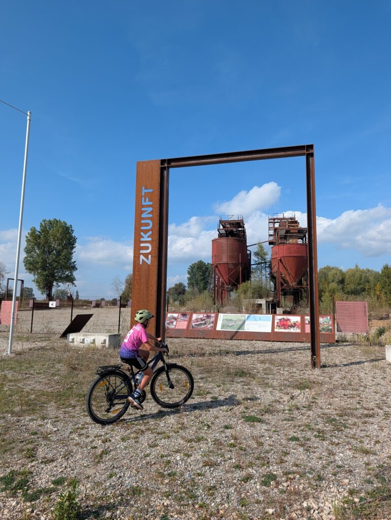 Kind mit Fahrrad vor dem Stahlrahmen „Zukunft“ an der Landmarke Donaumoos
