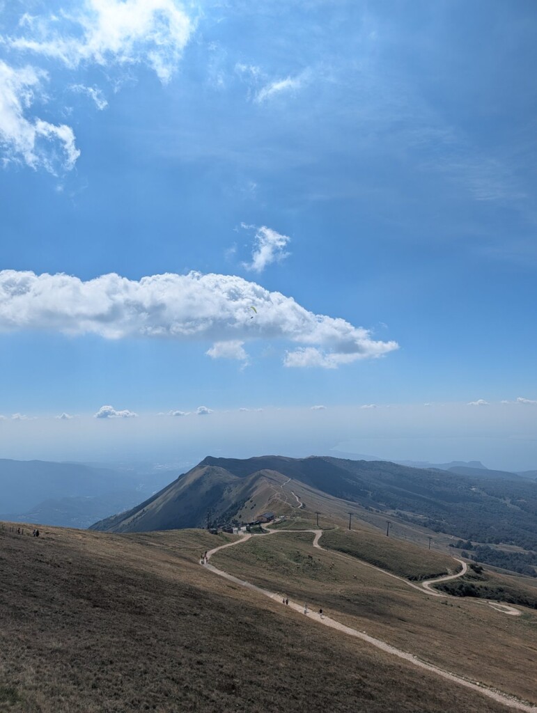 Wanderweg über den Bergrücken bei Costabella, am Himmel ein Gleitschirmflieger