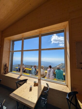 Panoramafenster einer Berghütte am Monte Baldo mit Blick auf die Sonnenterrasse