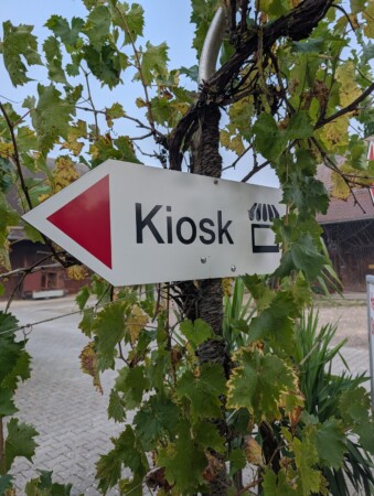 Wegweiser zum Kiosk auf dem Campingplatz zwischen Weinlaub